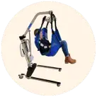Image of a woman in a blue lift sling being suspended in the air by an electric hoyer lift, against a cream circular background