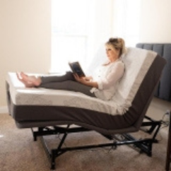 Image of woman reading a bed in a Flexabed brand bed. The legs and head of the hospital bed are elevated.